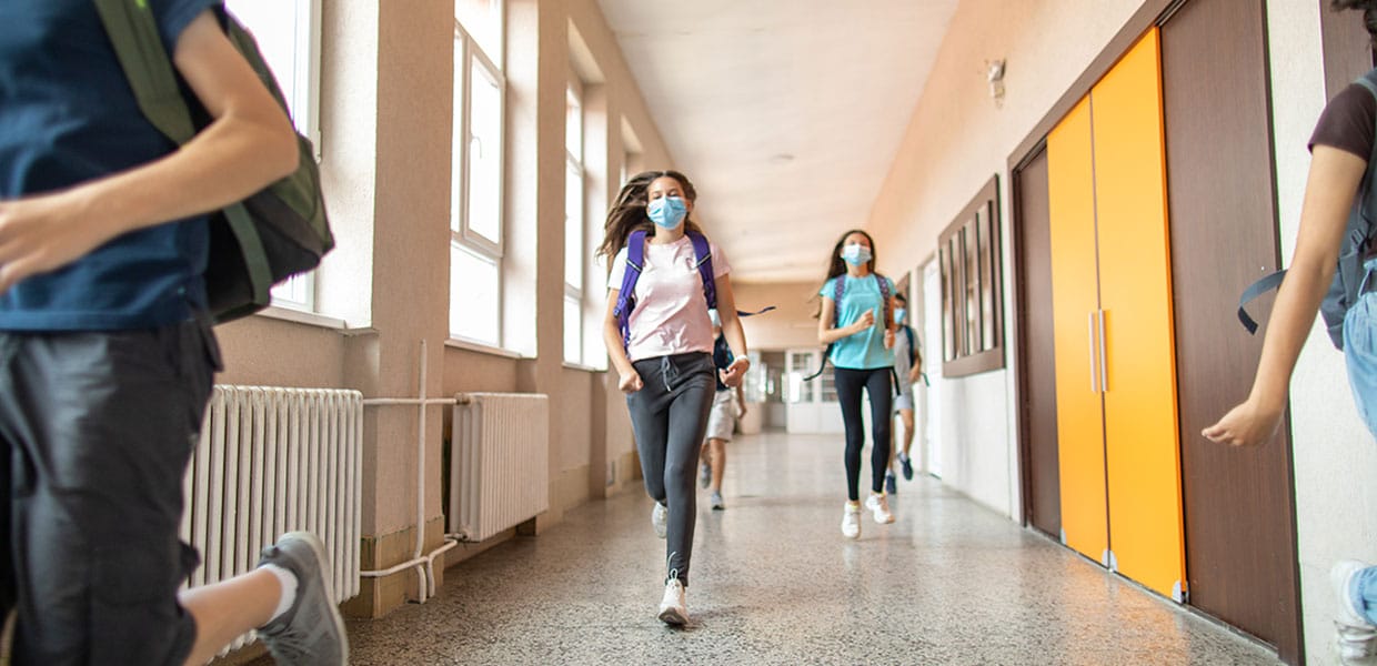 school-students-wearing-masks-running-down-the-hallway-iStock-1240x600