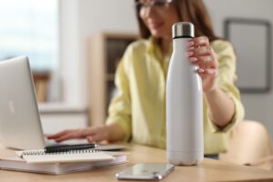 Woman holding thermos bottle at workplace.